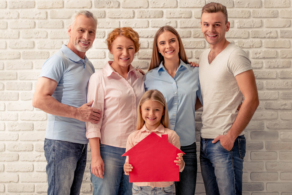 Glückliche Familie steht vor einer Wand und freut sicht.